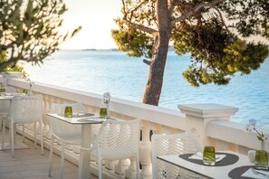 Een terras met witte stoelen en tafels, met uitzicht op een waterpartij.