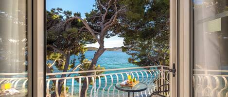 Un balcon offrant une vue dégagée sur la mer, une table avec un plateau de nourriture et une chaise.