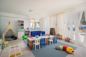 Ein Spielzimmer für Kinder mit einem Tisch, Stühlen, Spielzeug und einem Zelt.