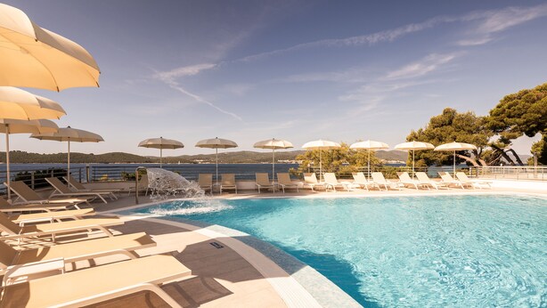 A poolside area with lounge chairs and umbrellas, overlooking a body of water. - Bellevue Maradiso Village by Aminess (Orebic)