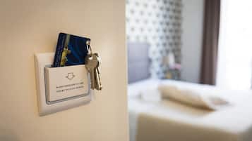 Quarto de hotel com cama, mesa de cabeceira e suporte de cartão de radiofrequência na parede, com chaves.