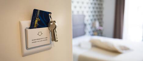 A hotel room with a bed, a nightstand, and a wall-mounted radio frequency card holder with keys.