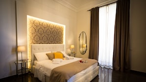Un dormitorio bien iluminado con una cama grande, una mesita de noche con lámpara, un espejo y una ventana con cortinas.