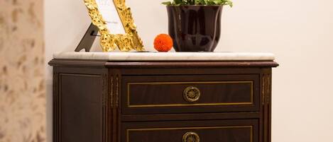 A dark wooden nightstand with three drawers and a gold frame on top.