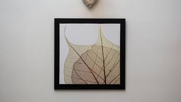 Een lijstwerk met een blad erop hangt aan een muur, met erboven een wandlamp.