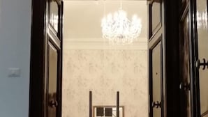 Vestíbulo de hotel con candelabro, espejo sobre una consola y felpudo en los escalones.