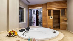 A modern bathroom with a freestanding bathtub, a vanity with a mirror, and a fruit bowl with a drink on the counter. - Crowne Rose AlSahafa Hotel (Riyadh)