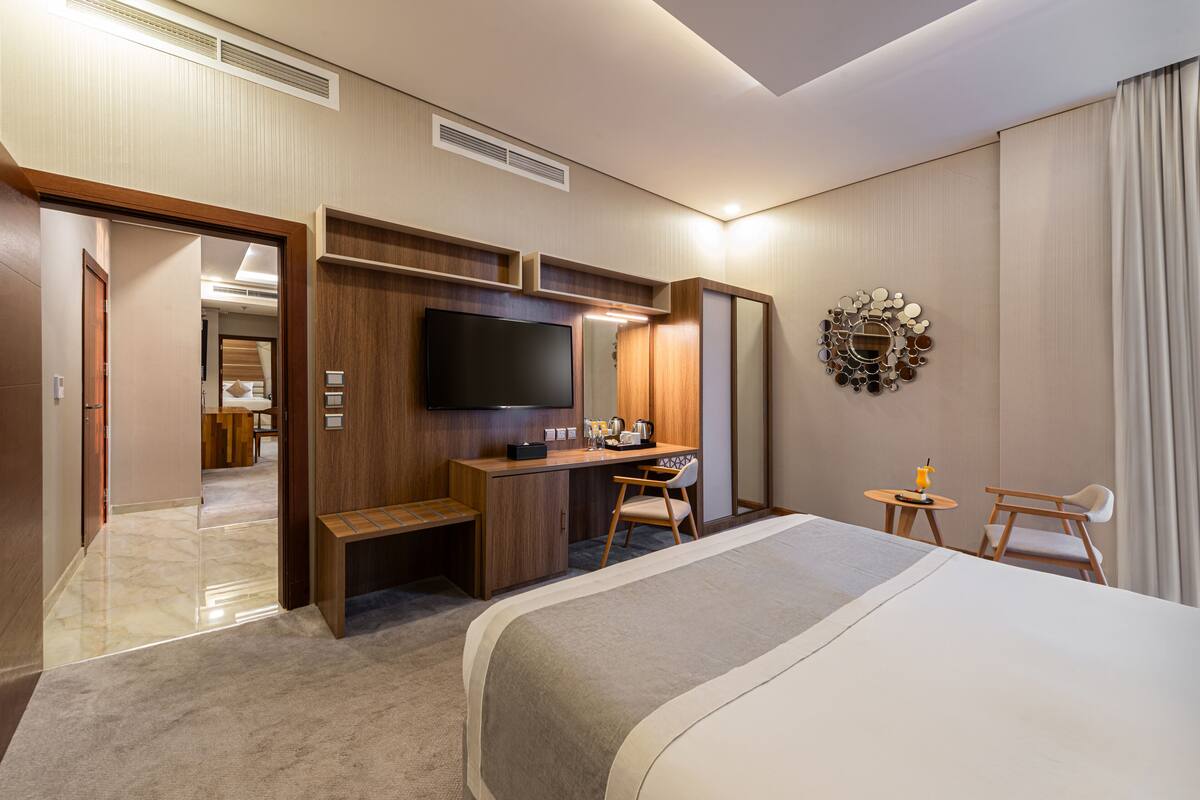 A hotel room with a bed, desk, chair, TV, and a mirror.