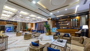 A spacious lobby with multiple seating areas, a reception desk, and a bar. - Crowne Rose AlSahafa Hotel (Riyadh)