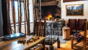 A cozy room with a stone fireplace, wooden furniture, and a painting on the wall.