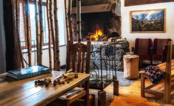 A cozy room with a stone fireplace, wooden furniture, and a painting on the wall.