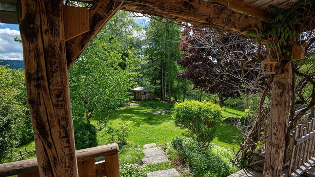 A wooden pergola with a stone staircase leading to a lush garden.