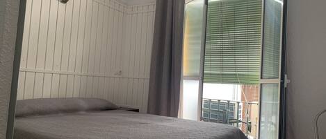 Un dormitorio con una cama, una ventana con persianas y un equipo de aire acondicionado.