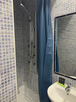 A bathroom with a shower, a sink, and a mirror. - Hostal Alcobia (Seville)
