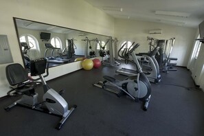 Un gimnasio con equipo de ejercicio, un espejo grande y pelotas de gimnasia.