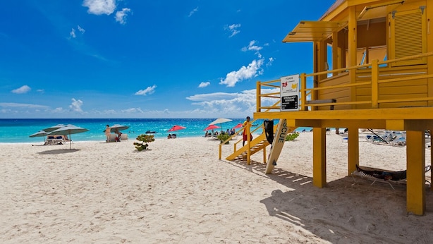 Ein Rettungsturm am Strand, mit blauem Himmel und türkisblauem Wasser.