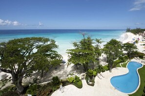 Un resort con spiaggia, piscina e rigogliosa vegetazione.
