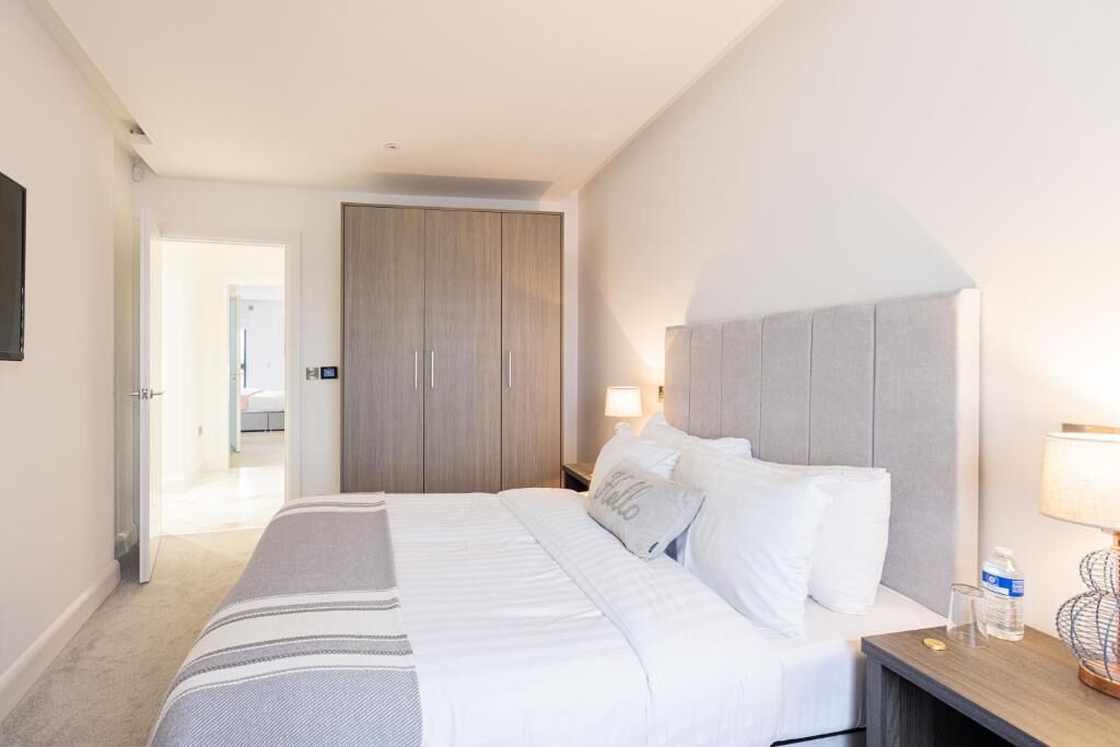 Una habitación de hotel con cama, mesita de noche, lámpara y armario.