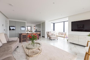 A modern living space with a sofa, a coffee table, a dining area, and a kitchen. - Curran Gate Luxury Apartments, Portrush (Portrush)
