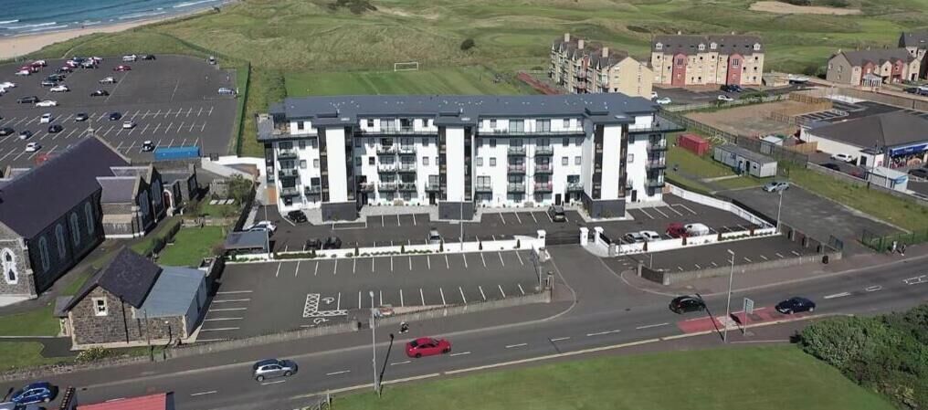 A multi-story building with a parking lot in front.