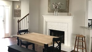 Un comedor con mesa y sillas de madera, una chimenea blanca y un ventilador de techo.