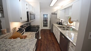 Cocina compacta con armarios blancos, microondas, estufa y lavabo.