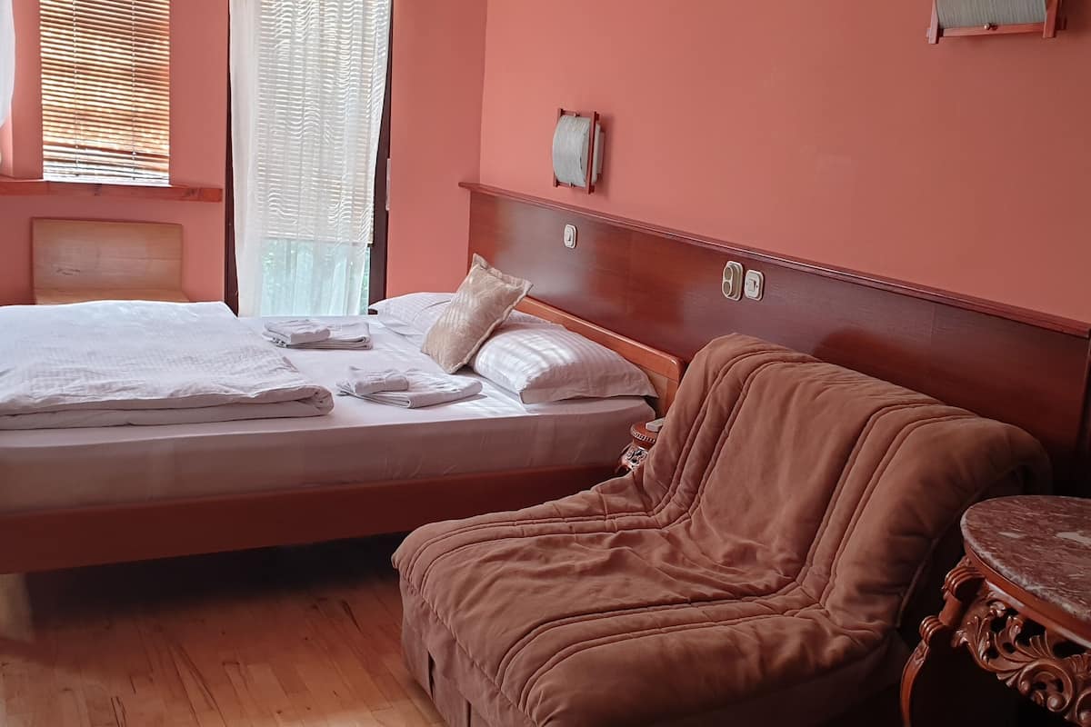 Una habitación con cama, sofá, una mesita y un espejo.