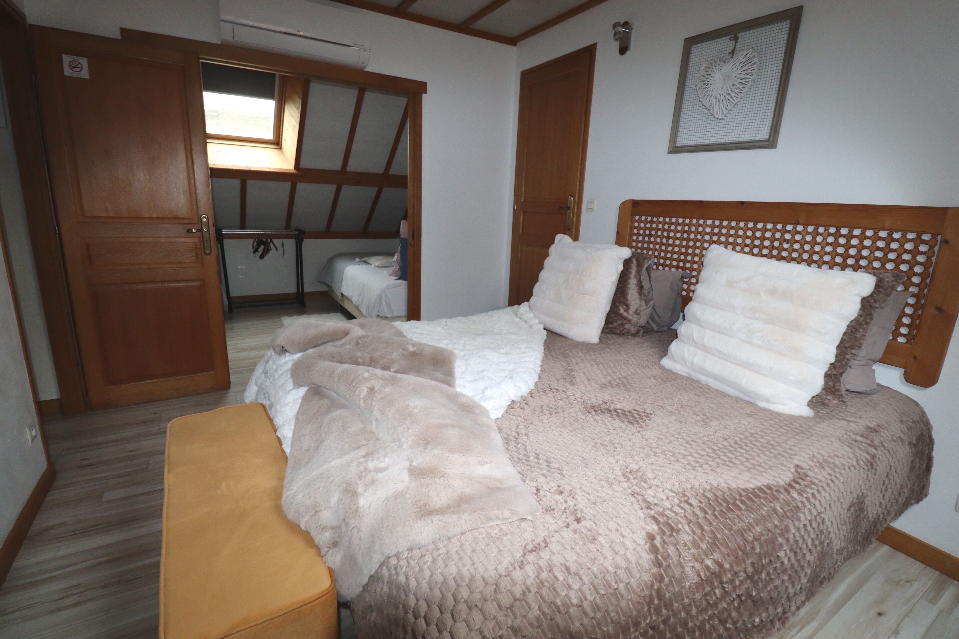 Quarto com uma cama, um banco, um guarda-roupa e uma porta.