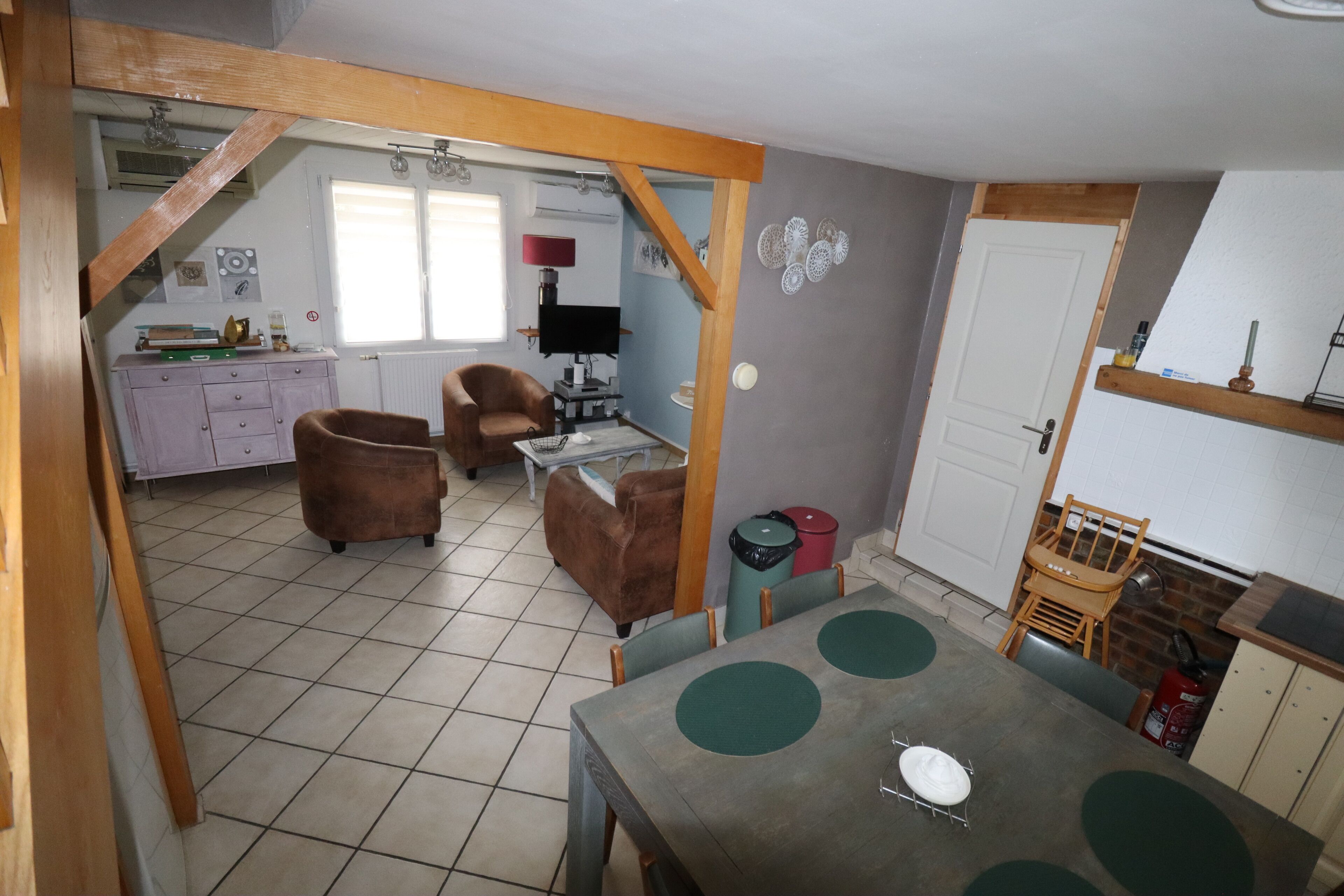 A dining area with a table, chairs, and a kitchen in the background.