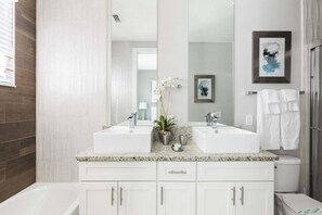 A modern bathroom with two sinks, a large mirror, and a shower.