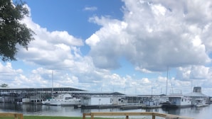Une terrasse en bois avec un banc donnant sur une marina où sont amarrés des bateaux et des quais.