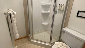 A shower with a glass door, a toilet, and a towel rack. - Oceanview Queen Bedroom - Mayne Island Resort (Mayne Island)