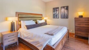Een keurig opgeruimde slaapkamer met een houten bed, nachtkastjes en een dressoir.