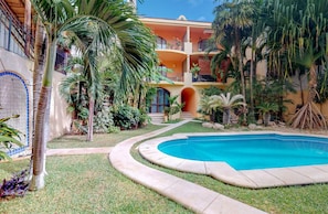 Una piscina rodeada de palmeras y un edificio con fachada de azulejos.