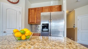 A kitchen with granite countertops, a stainless steel refrigerator, wooden cabinets, and a clock on the wall. - Lovely Long Term/STR Corporate, Family Near I20,Airport,Downtown,Airport (Austell)