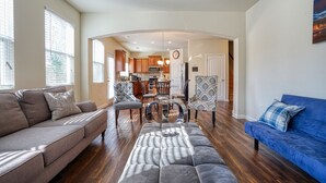 A spacious living room with a sofa, a blue couch, and a patterned chair. A dining table with chairs is in the background. - Lovely Long Term/STR Corporate, Family Near I20,Airport,Downtown,Airport (Austell)