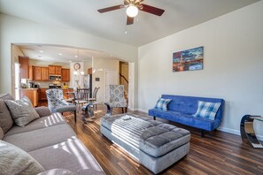 A spacious living room with a blue sofa, grey ottoman, and a dining area with a chandelier. - Lovely Home Conveniently Located  for Corporate,Family & Individual STays (Austell)