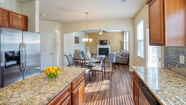 A spacious kitchen with granite countertops, a stainless steel refrigerator, and a dining area with a fireplace. - Lovely Long Term/STR Corporate, Family Near I20,Airport,Downtown,Airport (Austell)