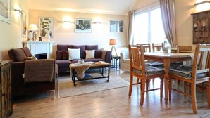 Ein gemütliches Wohnzimmer mit einer Sofagarnitur, einem Couchtisch und einem Esstisch mit Stühlen.