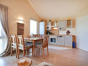 Une cuisine compacte comprenant un coin repas, des chaises en bois, une table à manger et un four encastré.
