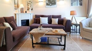 Ein gemütliches Wohnzimmer mit Kamin, zwei Sofas, einem Couchtisch und Wandlampen.