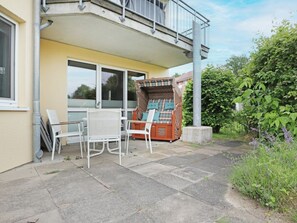 Une terrasse avec des meubles d’extérieur, une petite table et une poubelle.