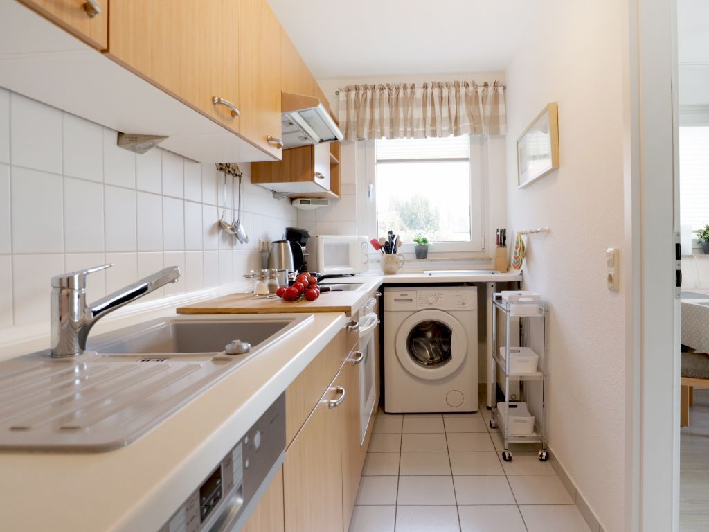 Een kleine keuken met een spoelbak, fornuis en wasmachine.