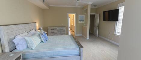 A bedroom with a bed, dresser, and a ceiling fan.