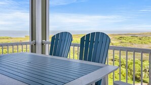 Un balcón con una mesa y dos sillas, con vistas al paisaje costero.