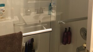 Un bagno con box doccia in vetro, lavandino bianco e portasciamani.