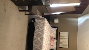 Una camera da letto con un letto, un comodino, una lampada a parete e un quadro incorniciato.