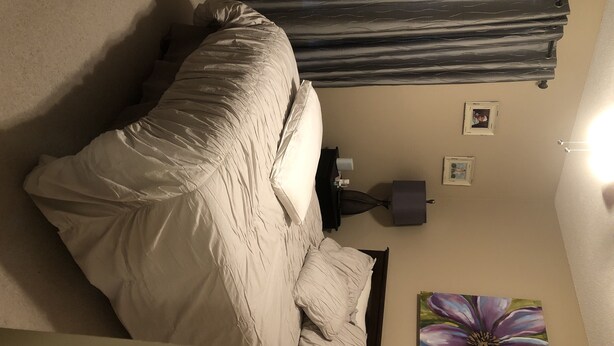 Una camera da letto con un letto, un comodino, una lampada e un quadro appeso al muro.
