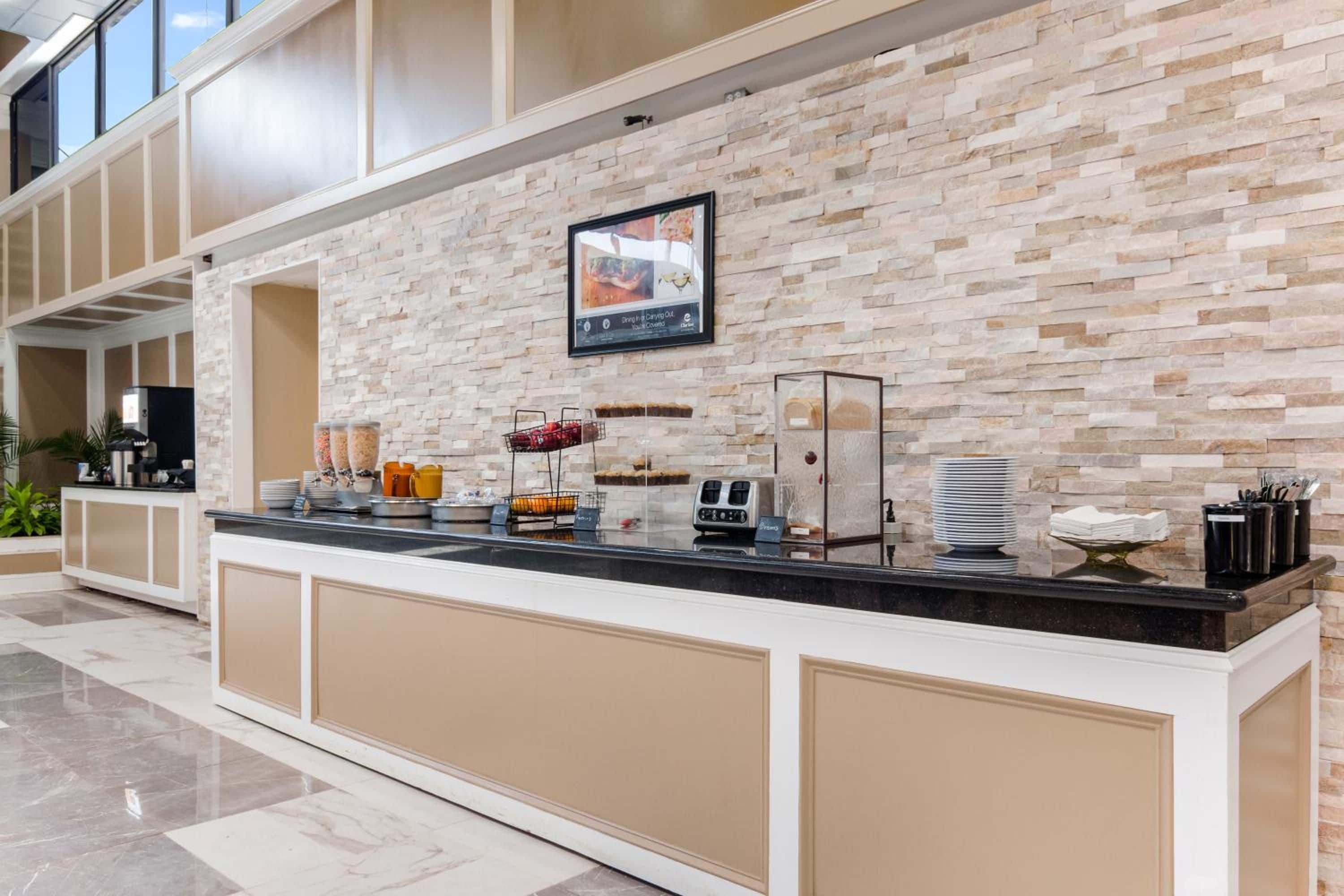 Un comptoir de buffet avec un mur en pierre en arrière-plan, un menu encadré et divers distributeurs de nourriture et de boissons.