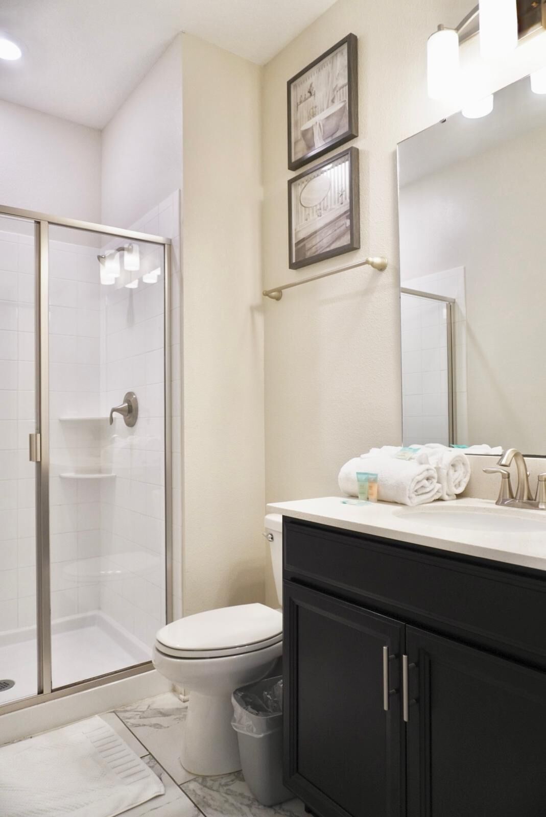 A bathroom with a glass-enclosed shower, a toilet, a sink with a mirror, and a cabinet.
